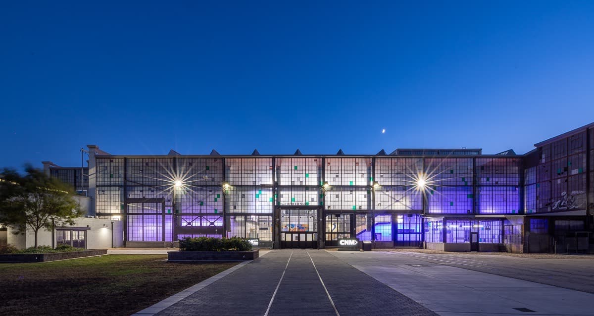 The CNM Railyards Film School lit purple at dusk, rail lines running toward its doors