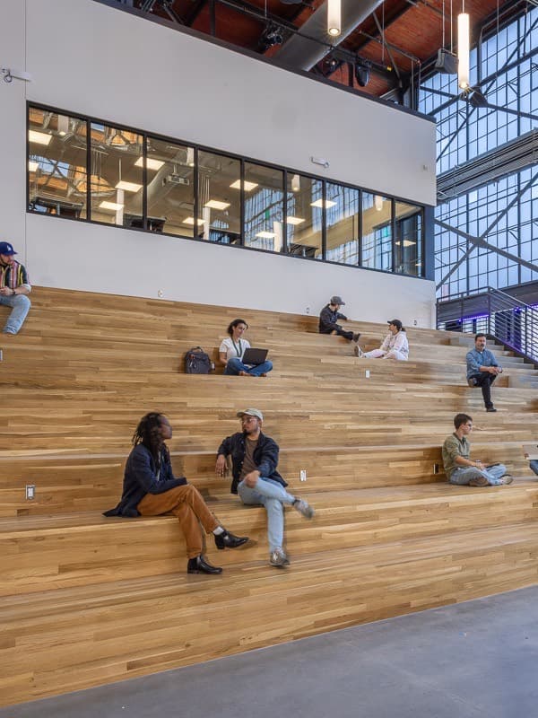 Students on the wooden study steps of a steel-framed hall